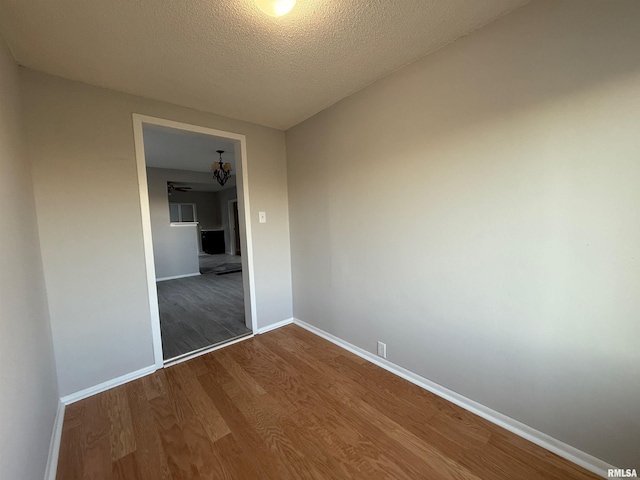 528 Cass St, East Peoria, IL 61611 - spare room featuring dark wood-style floors, baseboards, a chandelier, and a textured ceiling