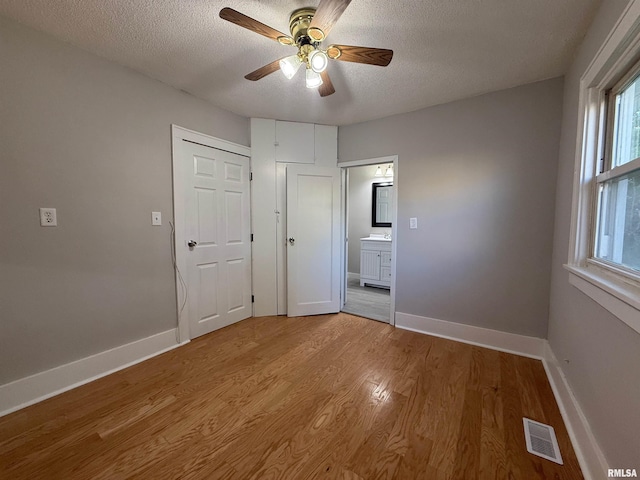 528 Cass St, East Peoria, IL 61611 - unfurnished bedroom featuring light wood-style floors, a textured ceiling, baseboards, and ceiling fan