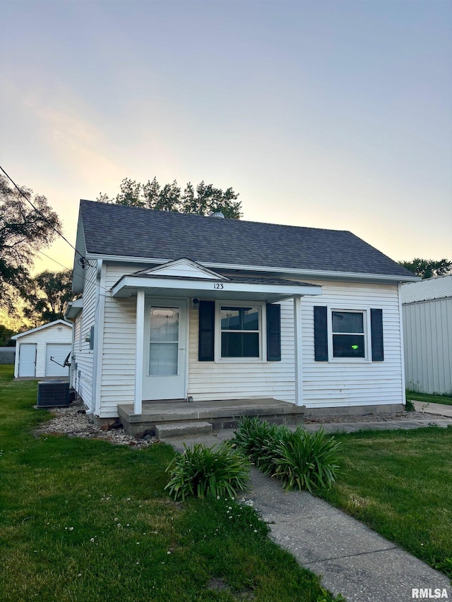 123 N Oak St, Williamsfield, IL 61489 - view of front facade featuring covered porch, a yard, roof with shingles, and central AC unit