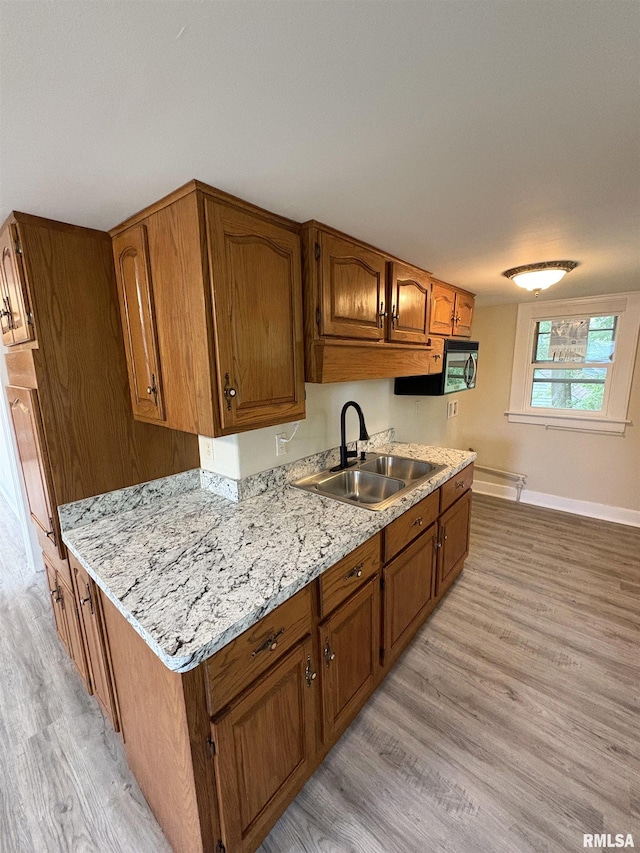 2704 N Dechman Ave, Peoria, IL 61603 - kitchen with a sink, light wood-type flooring, brown cabinetry, and baseboards
