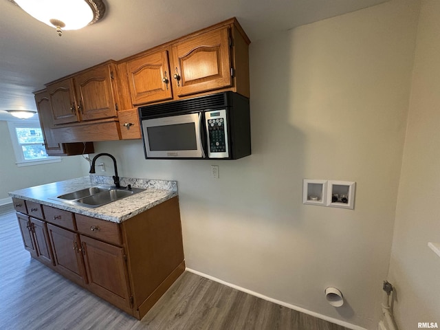 2704 N Dechman Ave, Peoria, IL 61603 - kitchen with stainless steel microwave, a sink, light wood-style flooring, baseboards, and light countertops