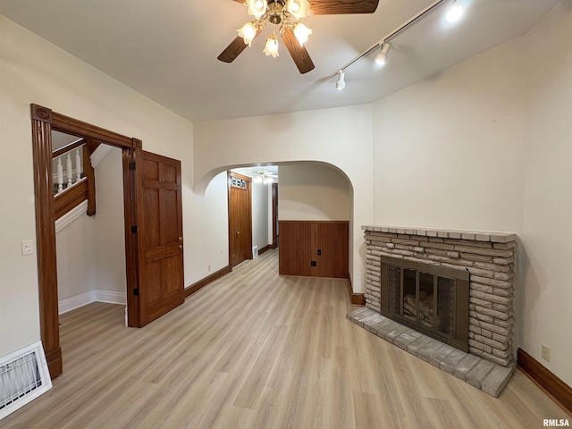 2704 N Dechman Ave, Peoria, IL 61603 - unfurnished living room with a ceiling fan, rail lighting, light wood finished floors, arched walkways, and baseboards