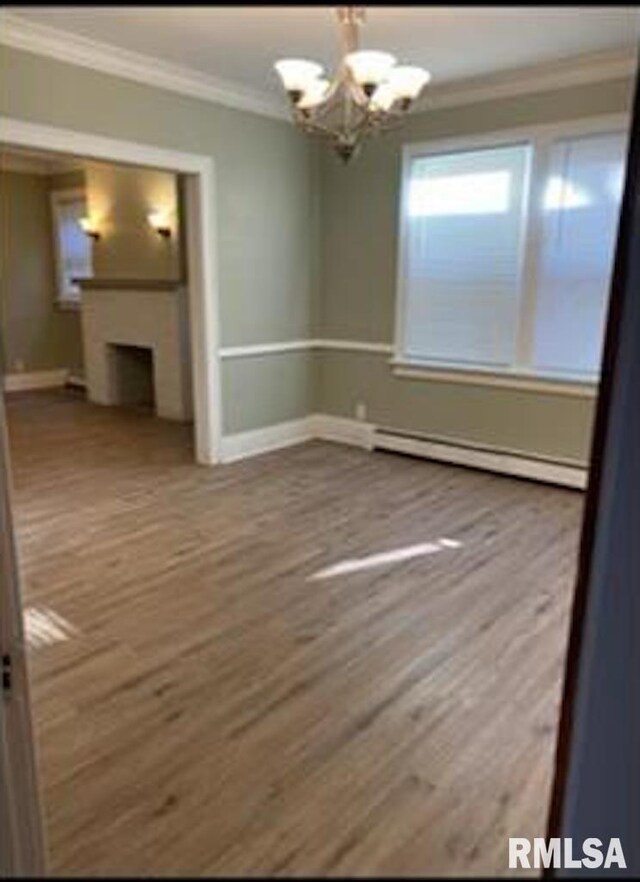 2405 N Sheridan Rd, Peoria, IL 61604 - unfurnished dining area with baseboard heating, crown molding, baseboards, wood finished floors, and a chandelier