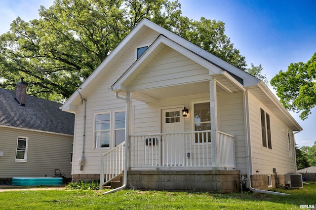bungalow-style home with central AC, covered porch, and a front lawn