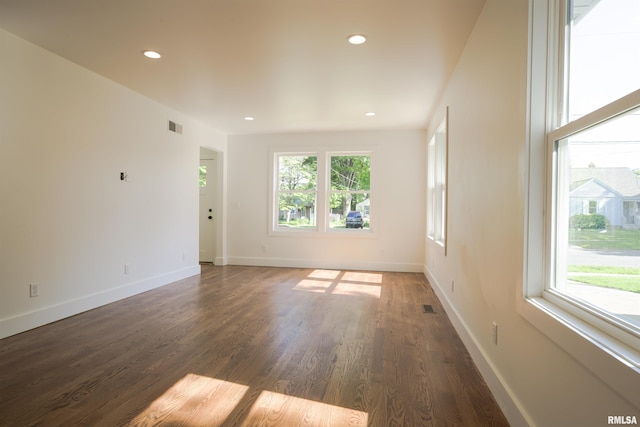 spare room with healthy amount of natural light, recessed lighting, wood finished floors, and baseboards