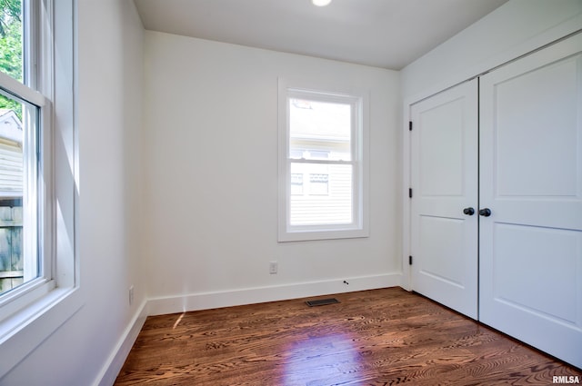 unfurnished bedroom with dark wood-style flooring, baseboards, and a closet
