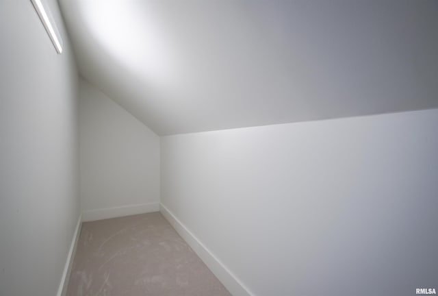 bonus room with vaulted ceiling, light colored carpet, and baseboards