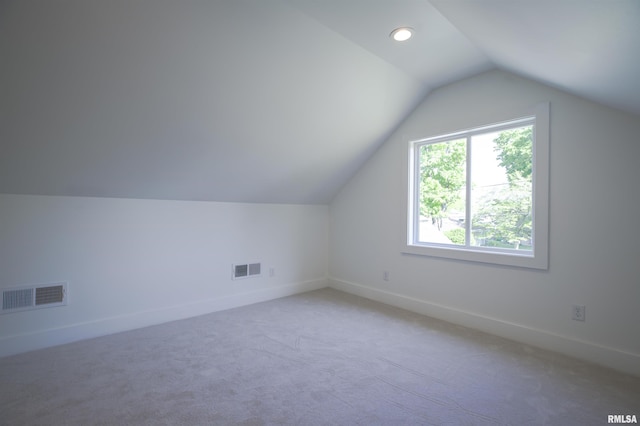 additional living space with vaulted ceiling, light carpet, and baseboards