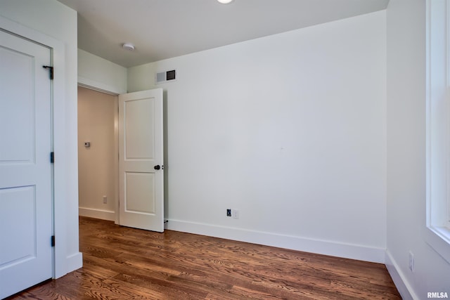 unfurnished bedroom with baseboards and dark wood-style flooring