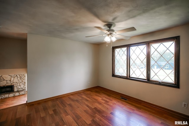 1529 W Richmar Rd, Peoria, IL 61615 - unfurnished room with ceiling fan, wood finished floors, baseboards, and a stone fireplace