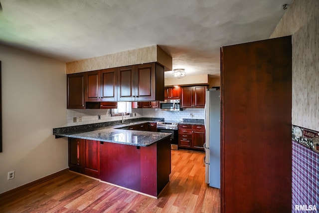 1529 W Richmar Rd, Peoria, IL 61615 - kitchen with stainless steel appliances, a peninsula, light wood-style flooring, backsplash, and dark stone countertops