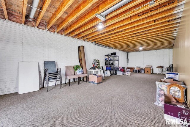 unfinished below grade area featuring carpet floors and brick wall