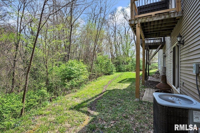 view of green lawn featuring central AC and a wooded view