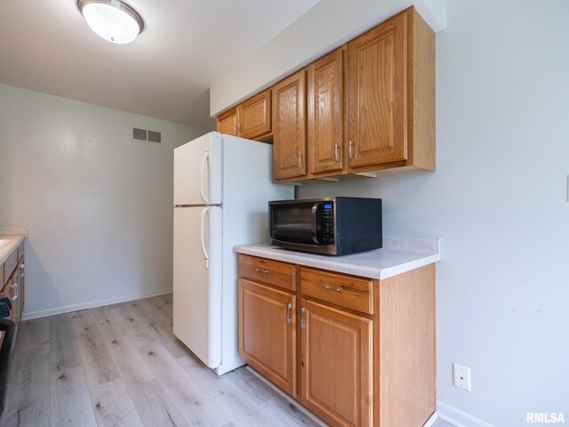 3509 S Dorothy Ct, Bartonville, IL 61607 - kitchen with light wood-type flooring, freestanding refrigerator, light countertops, brown cabinets, and baseboards