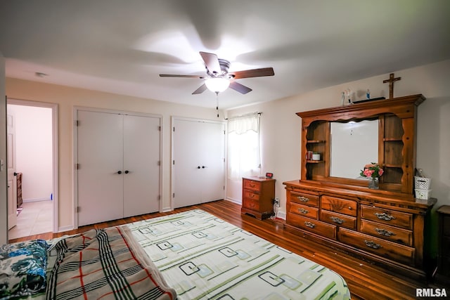 bedroom featuring light wood finished floors, multiple closets, baseboards, and ceiling fan