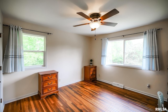 unfurnished room with healthy amount of natural light, hardwood / wood-style floors, a ceiling fan, and baseboards