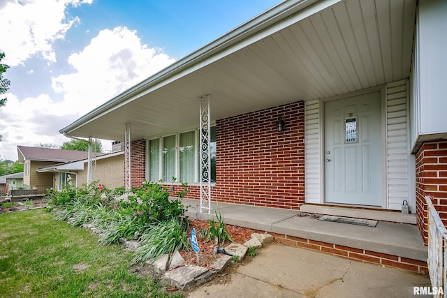 doorway to property featuring brick siding and covered porch
