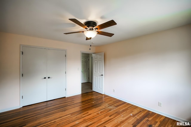 unfurnished bedroom with wood finished floors, a closet, baseboards, and a ceiling fan