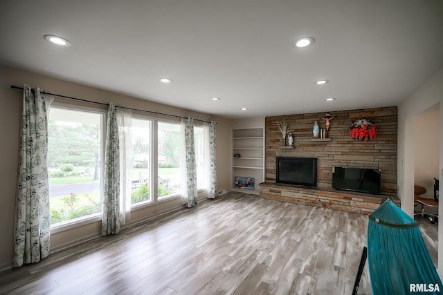 living area featuring recessed lighting, a fireplace, wood finished floors, and built in shelves