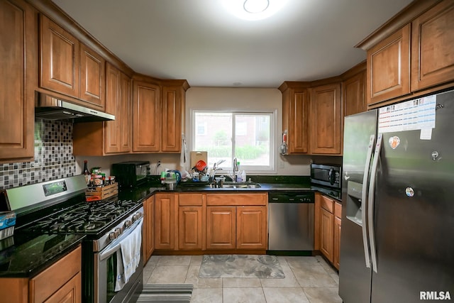 kitchen featuring stainless steel appliances, under cabinet range hood, and brown cabinetry