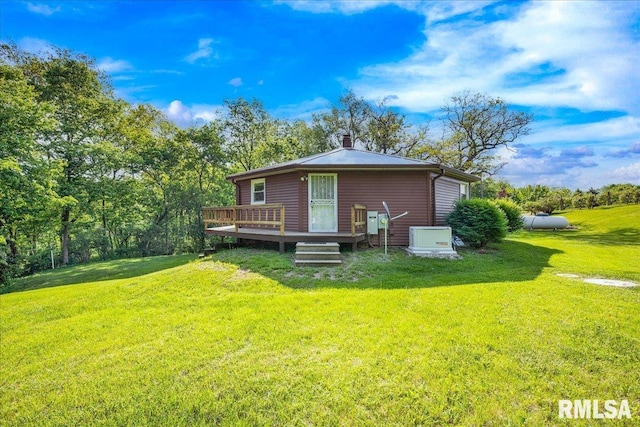 rear view of house featuring a wooden deck, a lawn, and a chimney