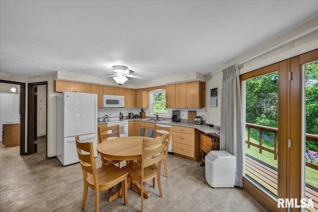 kitchen featuring white appliances, light countertops, a sink, ceiling fan, and light brown cabinetry