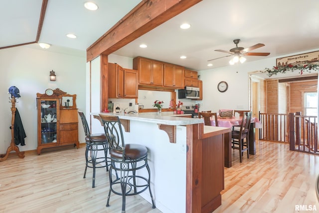 113 W Essex St, Glasford, IL 61533 - kitchen with appliances with stainless steel finishes, a kitchen bar, brown cabinets, light countertops, and a peninsula
