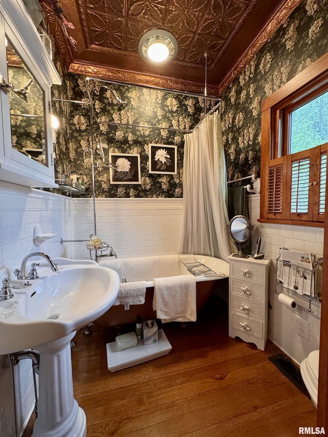 429 S Madison St, Macomb, IL 61455 - full bath featuring wallpapered walls, a wainscoted wall, wood finished floors, an ornate ceiling, and a tub