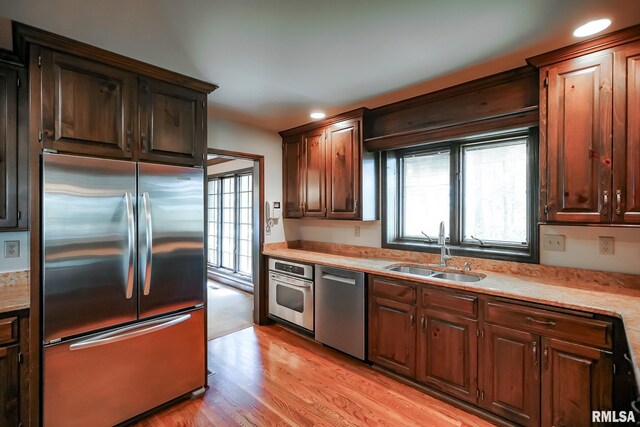 kitchen with appliances with stainless steel finishes, a sink, light countertops, light wood finished floors, and recessed lighting