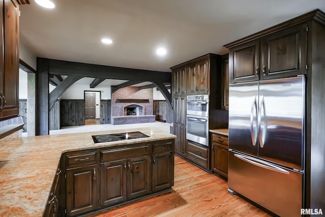 kitchen with appliances with stainless steel finishes, open floor plan, dark brown cabinetry, light wood finished floors, and recessed lighting