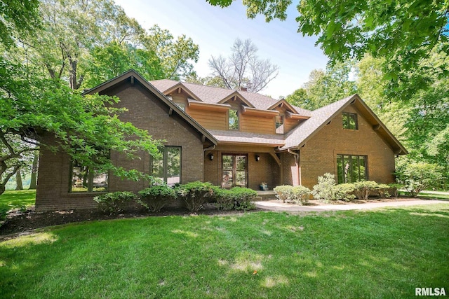 view of front of property featuring brick siding, a front lawn, and a shingled roof