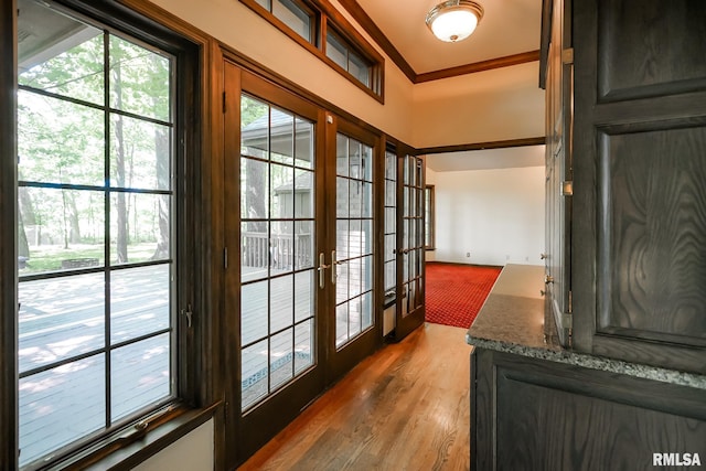 entryway with wood finished floors, crown molding, and french doors