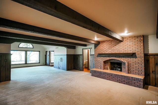 unfurnished living room featuring carpet floors, wainscoting, and a brick fireplace