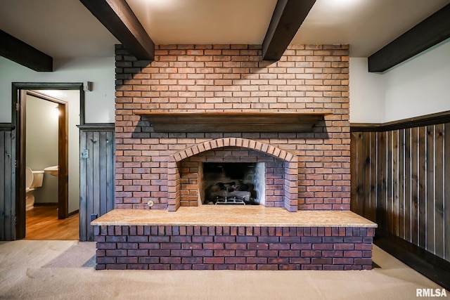 detailed view of beamed ceiling, a brick fireplace, and carpet