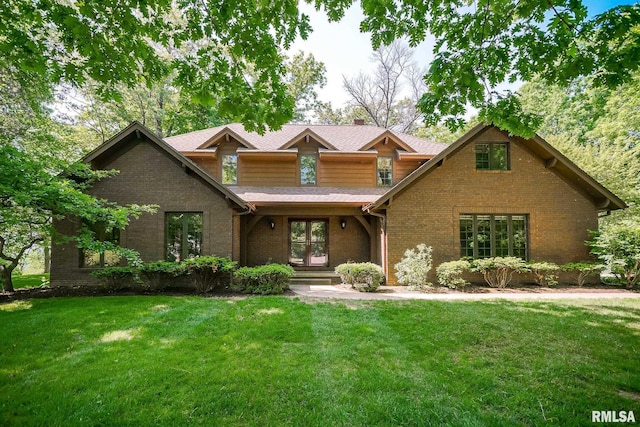 view of front facade featuring brick siding, a front yard, a shingled roof, and a chimney