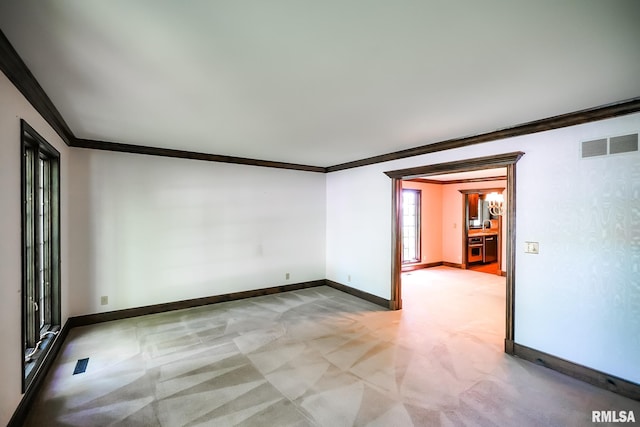 spare room with crown molding, baseboards, and light carpet