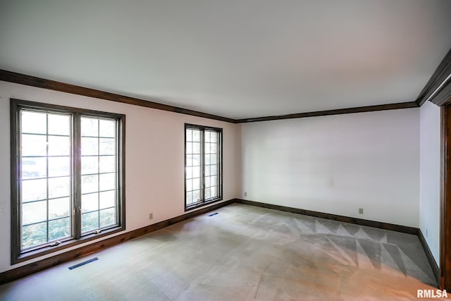 spare room with ornamental molding, light colored carpet, and baseboards