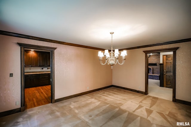 empty room featuring a chandelier, crown molding, light carpet, and baseboards