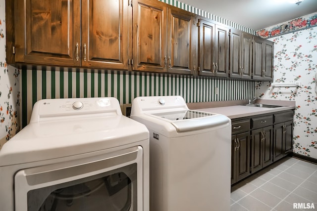 clothes washing area with wallpapered walls, cabinet space, washer and dryer, light tile patterned flooring, and baseboards