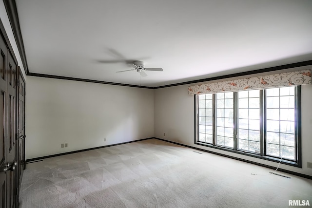 empty room featuring light carpet, a ceiling fan, ornamental molding, and baseboards