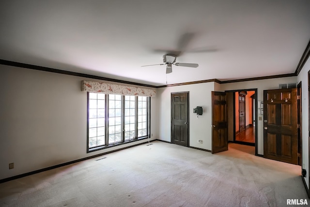 unfurnished bedroom featuring light colored carpet, baseboards, ornamental molding, and a ceiling fan