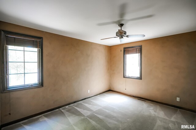 carpeted spare room featuring a ceiling fan and baseboards