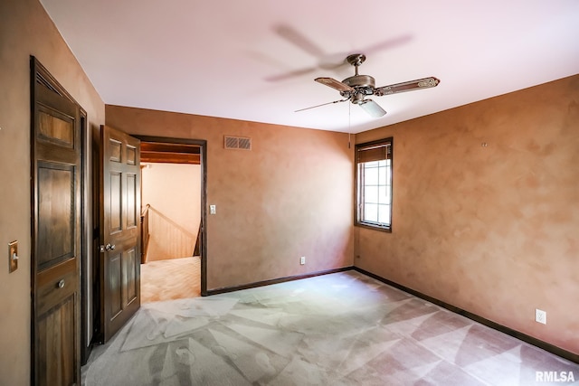 spare room with a ceiling fan, baseboards, and light colored carpet
