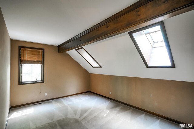 additional living space featuring a skylight, baseboards, and light colored carpet
