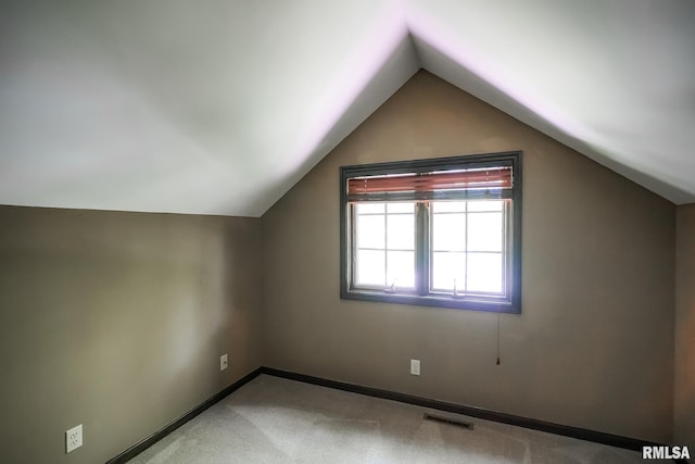 bonus room with lofted ceiling, light colored carpet, and baseboards