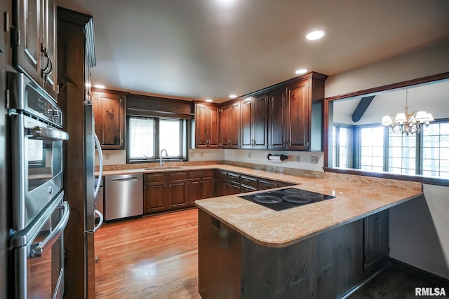 kitchen featuring appliances with stainless steel finishes, a peninsula, a sink, light countertops, and healthy amount of natural light