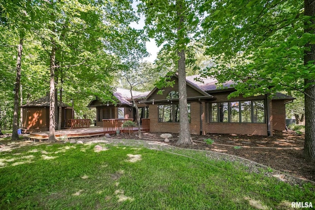 rear view of property featuring brick siding, a yard, and a deck