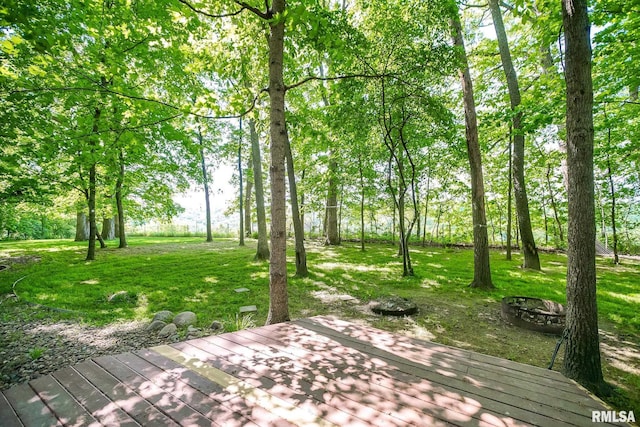 wooden terrace featuring an outdoor fire pit and a lawn