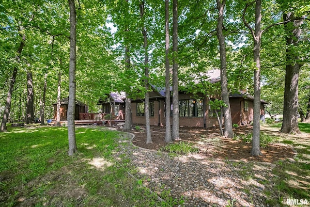 rear view of property with brick siding, a wooden deck, and a yard