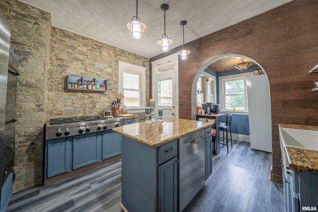 405 Washington St, Pekin, IL 61554 - kitchen featuring blue cabinets, stainless steel appliances, dark wood-style floors, arched walkways, and wood walls